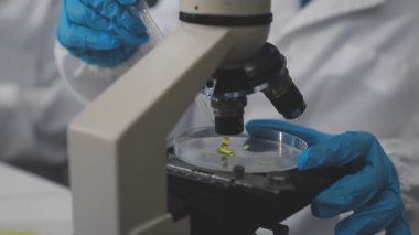 Bilim adamı elinde bir bardakla sıvı tutuyor.