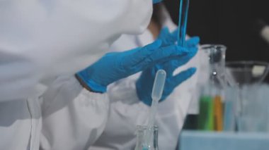 Laboratuvarda test tüpü ve kimyasal sıvıyla laboratuvar asistanının yakın plan fotoğrafı..