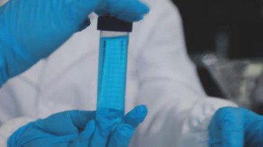 Laboratuvar asistanı elinde bir şişe tutuyor.