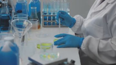 Laboratuvar kıyafetli bilim adamı laboratuvarda sıvıyla kimyasal deney yapıyor..