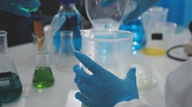 Mavi eldivenli laboratuvar asistanı test tüplerini sıvı halde tutuyor.