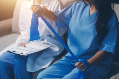 Erkek bir hasta üzerinde egzersiz band klinikte rehabilitasyon fizyoterapi kavramı ile onun kol germe egzersiz tedavisi verirken yardımcı doktor fizyoterapist