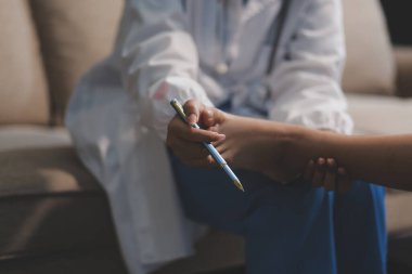 Kadın bir doktor, eklem iltihabı nedeniyle diz ağrısı olan yaşlı bir hastayı muayene eder. Hastaya iyileşme sürecinde yardım ediliyor, ağrı yönetimi ve hareket kabiliyetinin iyileştirilmesi üzerinde duruluyor..