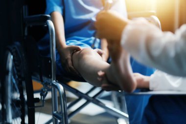 Kadın bir doktor, eklem iltihabı nedeniyle diz ağrısı olan yaşlı bir hastayı muayene eder. Hastaya iyileşme sürecinde yardım ediliyor, ağrı yönetimi ve hareket kabiliyetinin iyileştirilmesi üzerinde duruluyor..