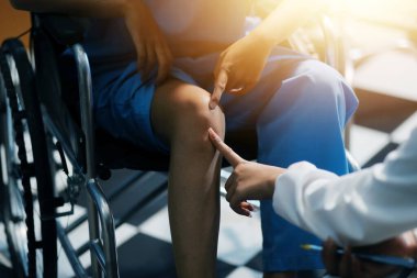 Kadın bir doktor, eklem iltihabı nedeniyle diz ağrısı olan yaşlı bir hastayı muayene eder. Hastaya iyileşme sürecinde yardım ediliyor, ağrı yönetimi ve hareket kabiliyetinin iyileştirilmesi üzerinde duruluyor..