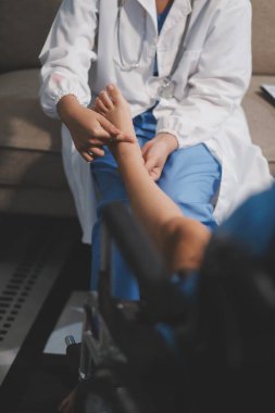 Kadın bir doktor, eklem iltihabı nedeniyle diz ağrısı olan yaşlı bir hastayı muayene eder. Hastaya iyileşme sürecinde yardım ediliyor, ağrı yönetimi ve hareket kabiliyetinin iyileştirilmesi üzerinde duruluyor..