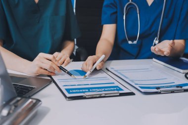 Medical team meeting analyzing blood test results in hospital laboratory. Doctors and scientists in lab coats are having a discussion about blood test result, holding test tubes and taking notes.