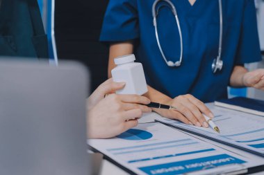 Medical team meeting analyzing blood test results in hospital laboratory. Doctors and scientists in lab coats are having a discussion about blood test result, holding test tubes and taking notes.