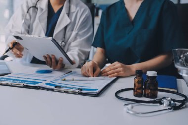 Medical team meeting analyzing blood test results in hospital laboratory. Doctors and scientists in lab coats are having a discussion about blood test result, holding test tubes and taking notes.