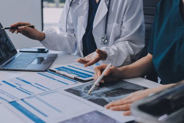 Medical team meeting analyzing blood test results in hospital laboratory. Doctors and scientists in lab coats are having a discussion about blood test result, holding test tubes and taking notes.