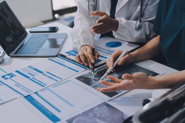 Medical team meeting analyzing blood test results in hospital laboratory. Doctors and scientists in lab coats are having a discussion about blood test result, holding test tubes and taking notes.
