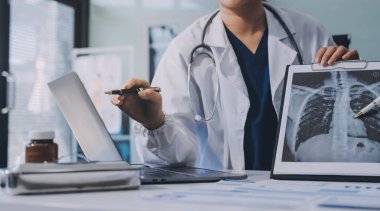 Medical team meeting analyzing blood test results in hospital laboratory. Doctors and scientists in lab coats are having a discussion about blood test result, holding test tubes and taking notes.
