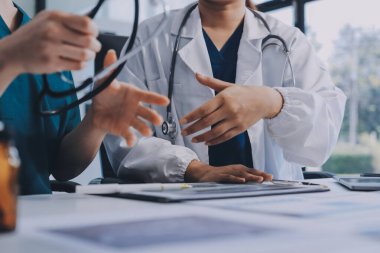 Medical team meeting analyzing blood test results in hospital laboratory. Doctors and scientists in lab coats are having a discussion about blood test result, holding test tubes and taking notes.