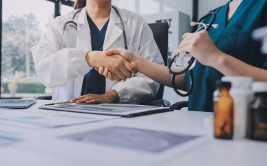 Medical team meeting analyzing blood test results in hospital laboratory. Doctors and scientists in lab coats are having a discussion about blood test result, holding test tubes and taking notes.