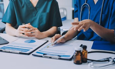 Medical team meeting analyzing blood test results in hospital laboratory. Doctors and scientists in lab coats are having a discussion about blood test result, holding test tubes and taking notes.