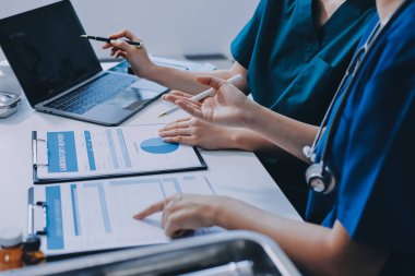 Medical team meeting analyzing blood test results in hospital laboratory. Doctors and scientists in lab coats are having a discussion about blood test result, holding test tubes and taking notes.