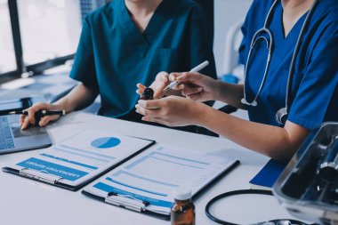 Medical team meeting analyzing blood test results in hospital laboratory. Doctors and scientists in lab coats are having a discussion about blood test result, holding test tubes and taking notes.