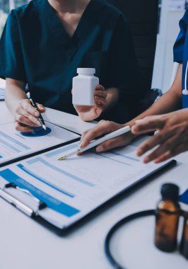 Medical team meeting analyzing blood test results in hospital laboratory. Doctors and scientists in lab coats are having a discussion about blood test result, holding test tubes and taking notes.
