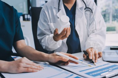Medical team meeting analyzing blood test results in hospital laboratory. Doctors and scientists in lab coats are having a discussion about blood test result, holding test tubes and taking notes.