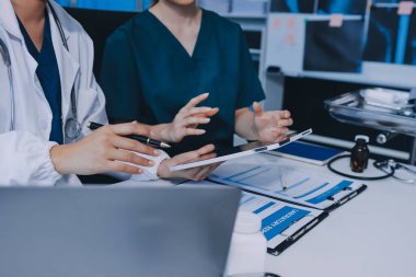 Medical team meeting analyzing blood test results in hospital laboratory. Doctors and scientists in lab coats are having a discussion about blood test result, holding test tubes and taking notes.
