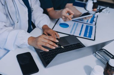 Medical team meeting analyzing blood test results in hospital laboratory. Doctors and scientists in lab coats are having a discussion about blood test result, holding test tubes and taking notes.