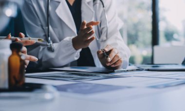 Medical team meeting analyzing blood test results in hospital laboratory. Doctors and scientists in lab coats are having a discussion about blood test result, holding test tubes and taking notes.