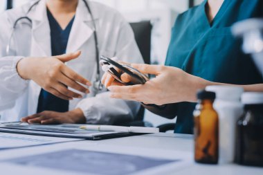 Medical team meeting analyzing blood test results in hospital laboratory. Doctors and scientists in lab coats are having a discussion about blood test result, holding test tubes and taking notes.