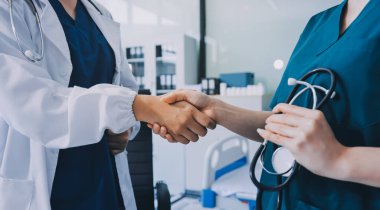 Medical team meeting analyzing blood test results in hospital laboratory. Doctors and scientists in lab coats are having a discussion about blood test result, holding test tubes and taking notes.