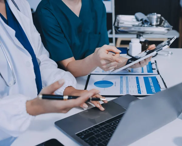Medical team meeting analyzing blood test results in hospital laboratory. Doctors and scientists in lab coats are having a discussion about blood test result, holding test tubes and taking notes.