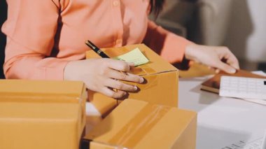 Beyaz tişörtlü, paketli ve dizüstü bilgisayarlı bir kadın.