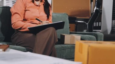 Ofiste elinde tabletle kağıda yazan genç bir kadın.