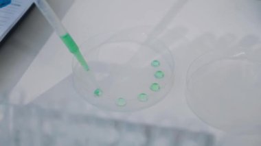 Test tüpleri ve pipeti olan bir laboratuvar asistanı.