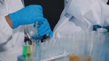 Laboratuvarda deney tüpü tutan bilim adamlarının ellerini kapatın.