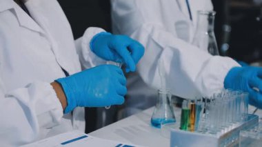 Mavi eldivenli ve test tüplü laboratuvar çalışanı.