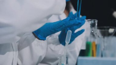 Cam tüp tutan koruyucu eldivenlerle laboratuvar asistanı.