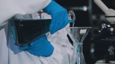 Kimyasal sıvıyla bardağı tutan bilim adamı