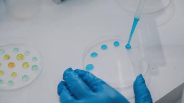 Mavi bir sıvıyı şeffaf plastik bir tüpte tutan elin yakınına.