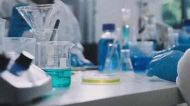 Laboratuvarda mavi takım elbiseli bir laboratuvar asistanı çalışıyor..