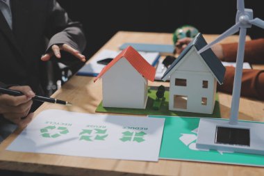 Ekip toplantısında, ESG konu sunumu için dizüstü bilgisayar kullanan Asyalı kadın, çok ırklı iş adamlarından oluşan genç bir gruba liderlik ediyor. Sürdürülebilir iş uygulaması, insanlar ev konseptinde çalışıyor