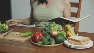 Genç bir kadın mutfakta kitap okuyor.