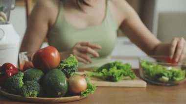 Kadın mutfakta taze sebzelerle yemek pişiriyor.