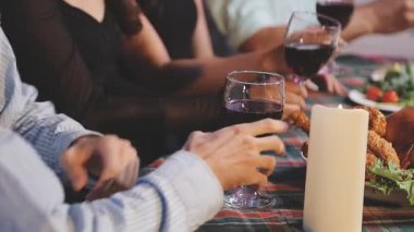 Yakın plan - Beyaz gömlekli ve siyah pantolonlu genç bir adam yemek odasında oturmuş, elinde bir şişe kırmızı şarap tutuyor.