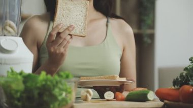 Genç bayan akşam yemeği için sandviç yapıyor.