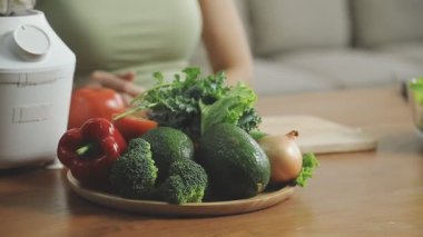 Genç bir kadın mutfakta taze sebze salatası tutuyor..