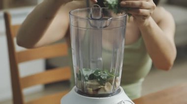 Kadın blender 'da sağlıklı sebze suyu hazırlıyor.