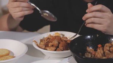 Mutfakta patates ve etle tavuk pişiren bir adamın yakın plan fotoğrafı.