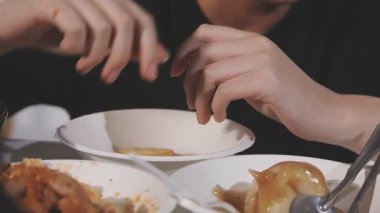 Beyaz tabakta tavuk budu yiyen bir kadın.