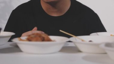 Genç adam mutfakta tavuk yiyor. Asya erkek yiyeceği.