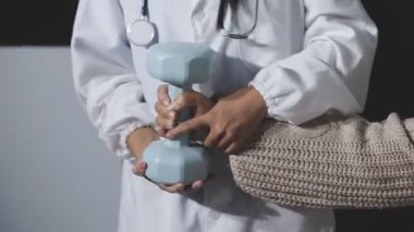 Evde fizyoterapistle egzersiz yapan mutlu yaşlı kadın. Emekli bir kadın rehabilitasyon seansı sırasında kişisel antrenörünün yardımıyla evde kollarını esnetiyor..