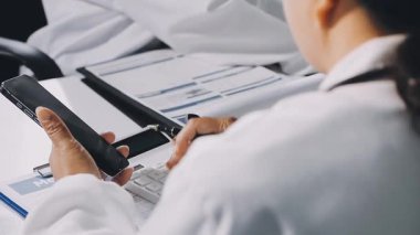 Modern bir hastanede elinde bir pano olan bir doktorun elini kapatıyoruz.